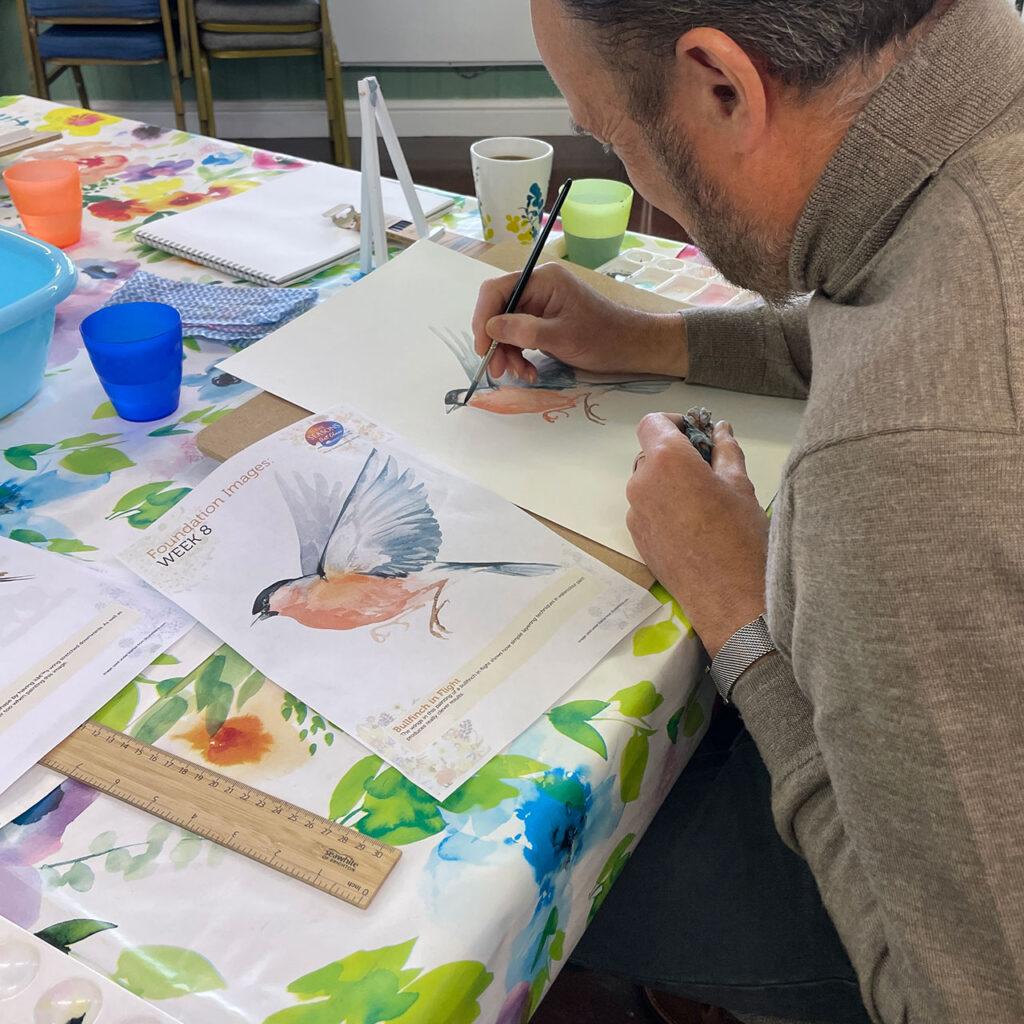 Man filling watercolour in bird painting