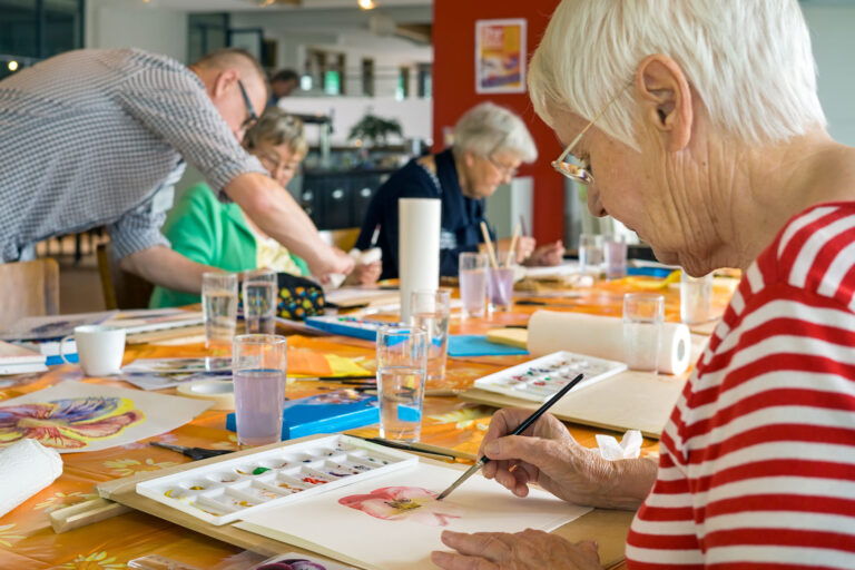 Woman painting in art class with people around her
